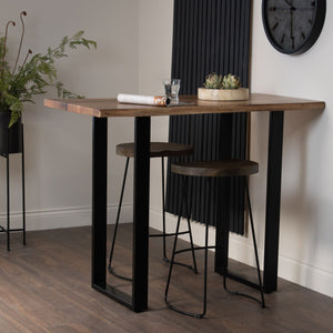 Live Edge Bar Table in BROWN Hill Interiors 22700 5050140270080 White glove delivery Dimensions: 100cm x 130cm x 70cm Weight: 39.14kg Volume: 0.24CBM This is the Live Edge Bar Table. Made from Indian hardwood (acacia), this Live Edge bar table is the perfect place to set up your home bar and has a stylish metal base, giving it an industrial luxe style. Elevate your home entertainment set-up with this stylish piece. 

The Live Edge wood creates real charm and character and helps you to bring a feel of the ou