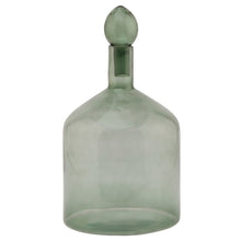 Load image into Gallery viewer, Smoked Sage Glass Bottle With Stopper in SAGE Hill Interiors 22981 5050140298183 Dimensions: 33cm x 18cm x 18cm Weight: 0.85kg Volume: 0.1CBM This is the Smoked Sage Glass Bottle With Stopper. This ornamental glassware is a perfect partner to our new Stamford furniture range, injecting some subtle and soothing tones to its display cabinets and surfaces. Matching taller shaped bottle and stopper available for a beautiful staggered height display.