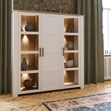 Load image into Gallery viewer, Bohol Large Display Cabinet in Riviera Oak/White Furniture To Go 801bhlv631-m482 5904767840563 The Bohol collection draws inspiration from its timeless charm and rustic style, embracing its simplicity and natural elegance. What truly sets this collection apart from others is its exquisite decor - featuring three colourways with an Oak finish. The subtle elegance of the light Riviera Oak contributes by adding a focal point to each piece. Also featuring black handles with soft close doors, making it truly sta