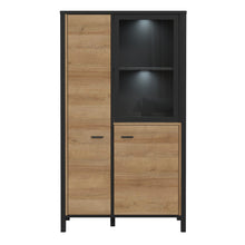 Load image into Gallery viewer, High Rock Small Display Cabinet in Matt Black/Riviera Oak Furniture To Go 801hrkv521-m197 5904767827199 High Rock, a captivating and contemporary collection which has a perfect blend of the Riviera Oak decor with deep black accents, this collection immediately captivates attention with its originality. The sleek black metal handles add a touch of elegance, while the tables boast robust metal legs in a frame-like design, contributing to a distinct loft character within the space. Beyond its striking aestheti