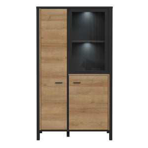 High Rock Small Display Cabinet in Matt Black/Riviera Oak Furniture To Go 801hrkv521-m197 5904767827199 High Rock, a captivating and contemporary collection which has a perfect blend of the Riviera Oak decor with deep black accents, this collection immediately captivates attention with its originality. The sleek black metal handles add a touch of elegance, while the tables boast robust metal legs in a frame-like design, contributing to a distinct loft character within the space. Beyond its striking aestheti