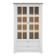 Load image into Gallery viewer, Illopa Iloppa Display Cabinet in Snowy Oak/Oak Nelson Furniture To Go 801tiqv722b-j99 5904767878481 Enhance the ambiance of your home with the exquisite Illopa collection, a seamless fit for any living space. Its most outstanding feature lies in the array of shapes it offers, granting you the freedom to artistically arrange every room in your house, from the inviting hall to the cozy living room. The captivating combination of beautiful white and oak imbues your home with a sense of tranquility, fostering a